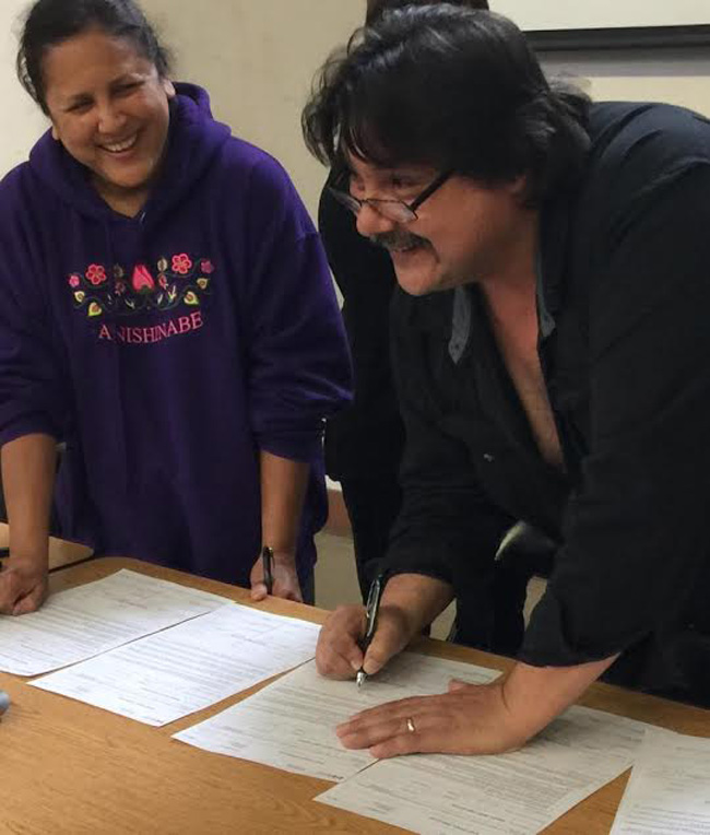 Henvey Inlet First Nation Chief Wayne McQuabbie with Councillor Brenda Contin signing Environment Permit Band Council Resolution  for Henvey Inlet Wind Project.    – Photo By Wanda McQuabbie.