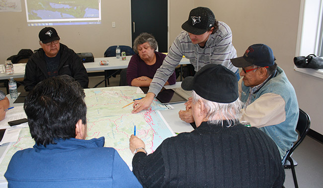 Elders and youth study maps together in their fight against aerial spraying. 