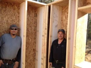 Two carpenters show how thick the walls are in the R66 home being built by SuperSHELL Homes Corporation partners Glen Chiblow and Ross MacLean for a community member in Garden River.